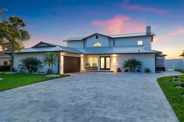 view of front of property featuring a garage, a yard, and french doors