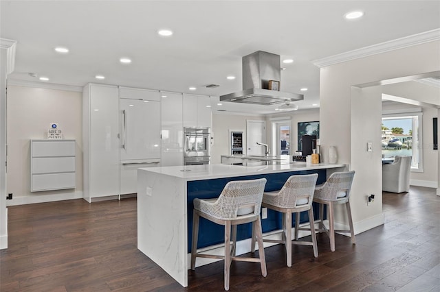 kitchen featuring crown molding, kitchen peninsula, white built in fridge, white cabinetry, and island exhaust hood