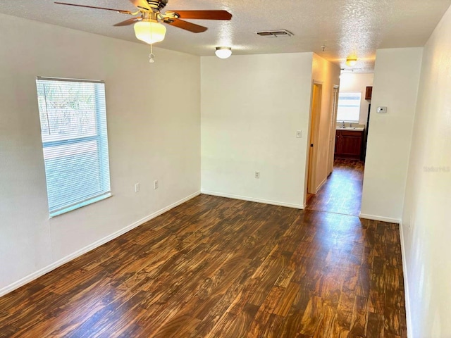 spare room featuring ceiling fan, dark hardwood / wood-style flooring, and a textured ceiling