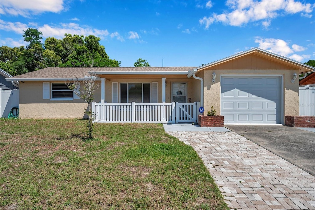 single story home featuring a porch, a garage, and a front yard