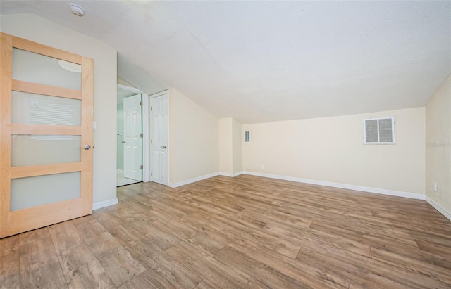 bonus room with lofted ceiling and light hardwood / wood-style flooring