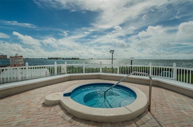 view of swimming pool featuring a hot tub and a water view