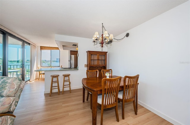 dining area with a chandelier, floor to ceiling windows, and light hardwood / wood-style flooring