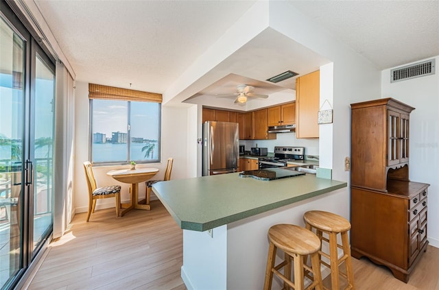 kitchen with kitchen peninsula, stainless steel appliances, light wood-type flooring, and a textured ceiling