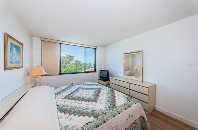 bedroom featuring hardwood / wood-style flooring, a textured ceiling, and a baseboard radiator