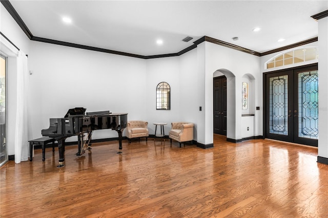 foyer featuring hardwood / wood-style flooring, crown molding, and french doors