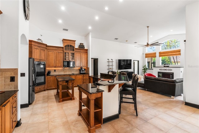 kitchen featuring a center island, a kitchen breakfast bar, tasteful backsplash, vaulted ceiling, and black appliances