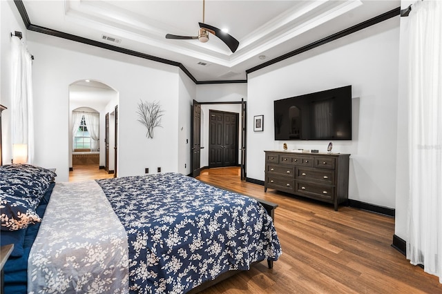 bedroom with wood-type flooring, connected bathroom, ceiling fan, and crown molding