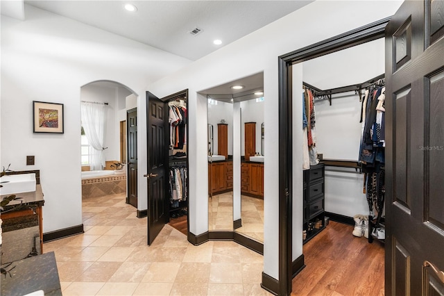 interior space featuring tile patterned flooring, a relaxing tiled tub, and vanity