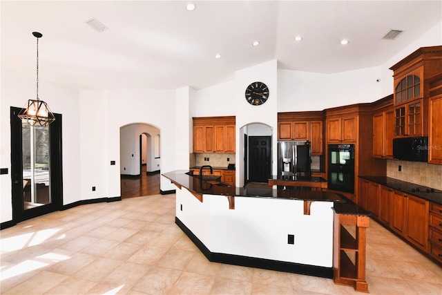 kitchen featuring tasteful backsplash, decorative light fixtures, a breakfast bar area, and black appliances