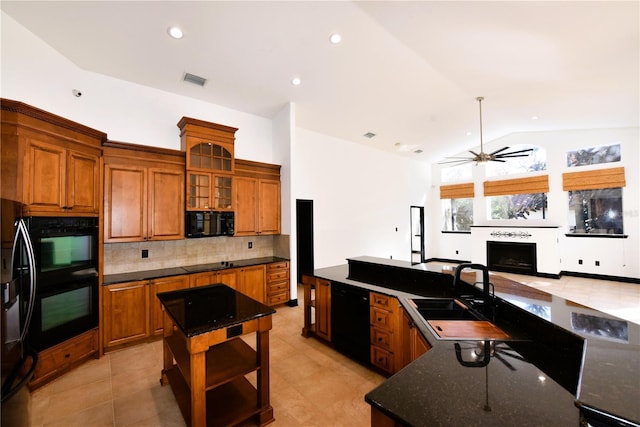 kitchen featuring vaulted ceiling, a kitchen island, tasteful backsplash, sink, and black appliances