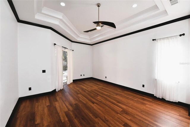 empty room featuring crown molding, dark hardwood / wood-style floors, a raised ceiling, and ceiling fan