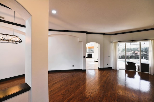 spare room featuring ornamental molding, dark hardwood / wood-style floors, and a chandelier