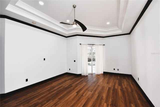 unfurnished room with dark wood-type flooring, ceiling fan, a tray ceiling, and crown molding