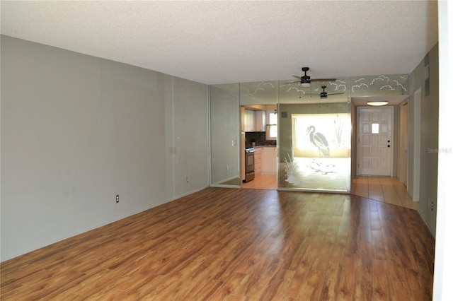 unfurnished living room with a ceiling fan, light wood-style flooring, and a textured ceiling