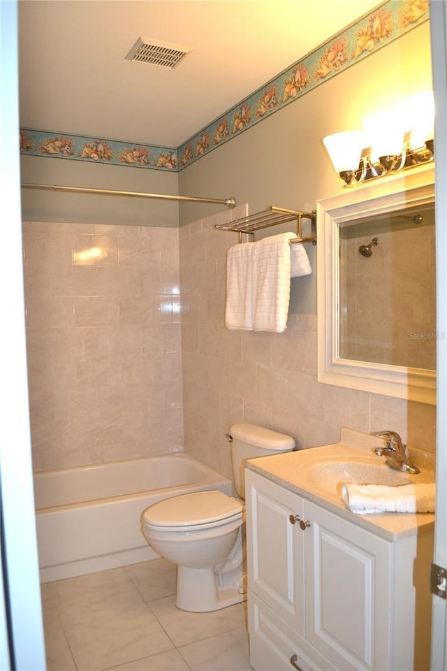 bathroom with tile patterned flooring, toilet, visible vents, tile walls, and shower / bathing tub combination