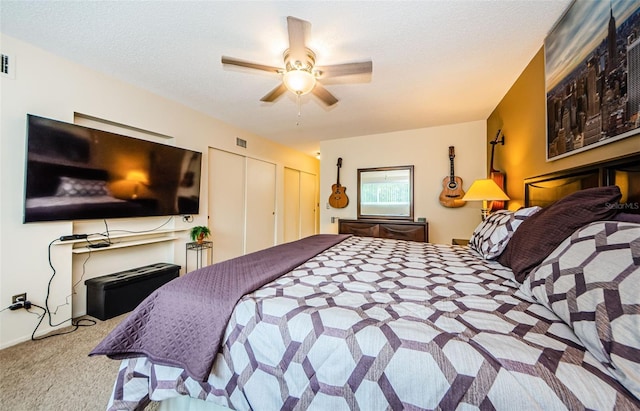 bedroom featuring carpet, two closets, visible vents, ceiling fan, and a textured ceiling