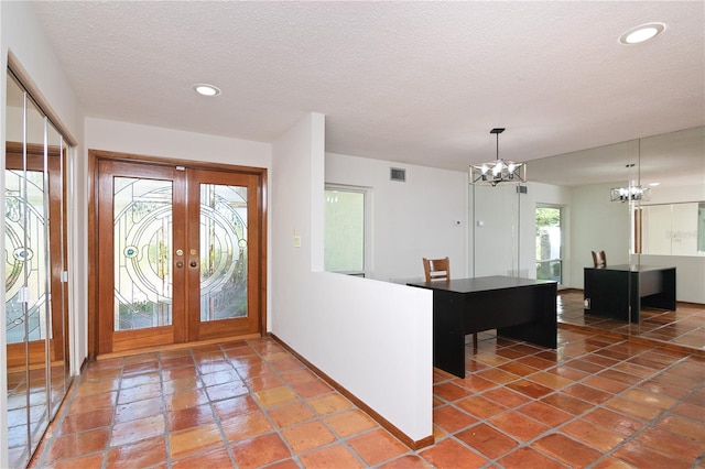 tiled foyer with a textured ceiling and a chandelier