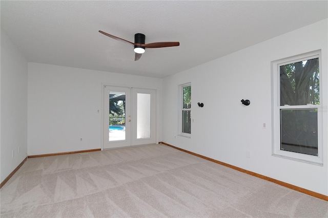 carpeted spare room featuring ceiling fan, a textured ceiling, and french doors