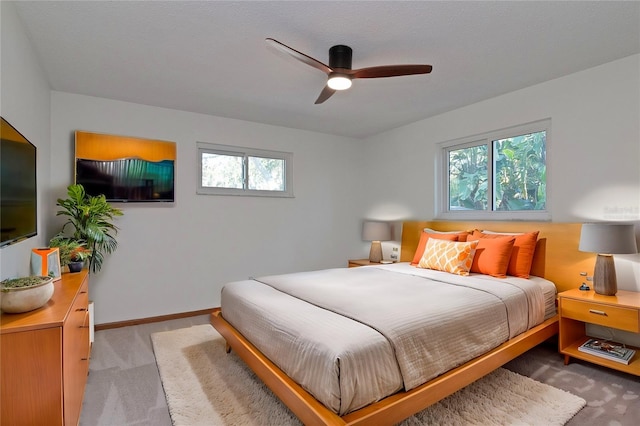 bedroom with ceiling fan, light colored carpet, and multiple windows