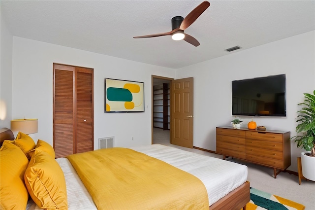 carpeted bedroom featuring ceiling fan, a textured ceiling, and a closet