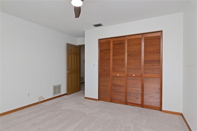 unfurnished bedroom featuring ceiling fan, light colored carpet, and a closet