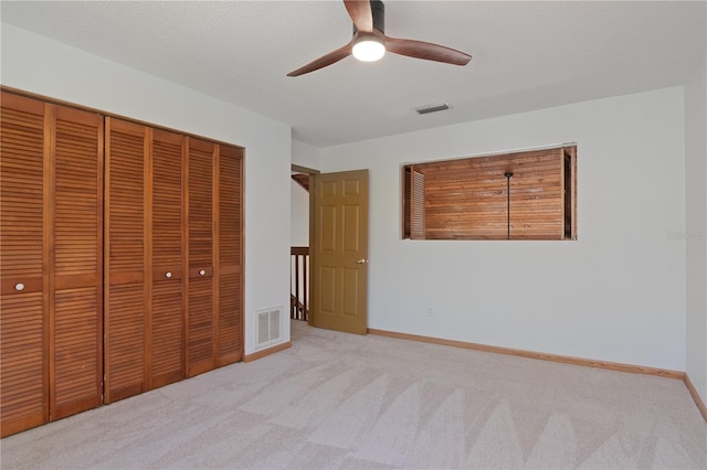 unfurnished bedroom featuring ceiling fan, light carpet, and a closet