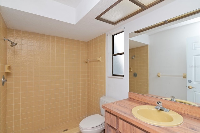 bathroom featuring toilet, vanity, and a tile shower