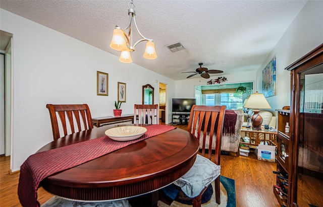 dining space featuring hardwood / wood-style floors, ceiling fan with notable chandelier, and a textured ceiling