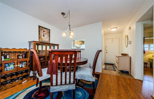 dining space featuring a chandelier, a textured ceiling, and hardwood / wood-style flooring