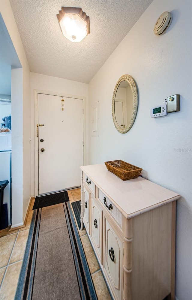 doorway to outside with light tile patterned floors, a textured ceiling, and washer / dryer