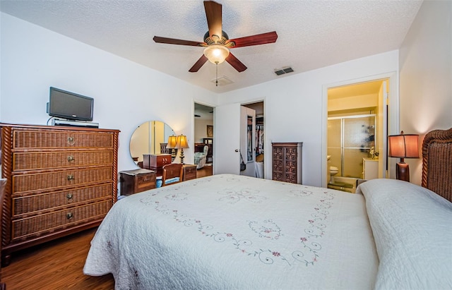 bedroom with ceiling fan, dark wood-type flooring, ensuite bathroom, a walk in closet, and a closet