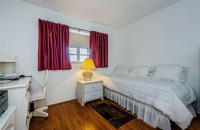 bedroom featuring dark hardwood / wood-style flooring and a textured ceiling