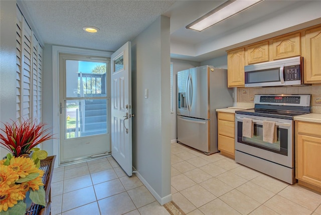 kitchen with tasteful backsplash, a textured ceiling, stainless steel appliances, light brown cabinets, and light tile patterned floors