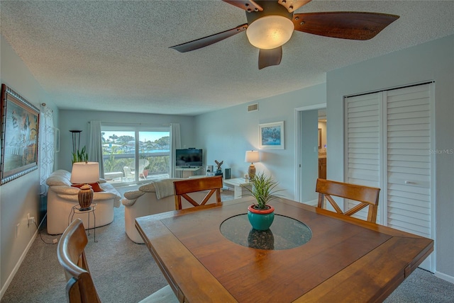 carpeted dining space featuring ceiling fan and a textured ceiling