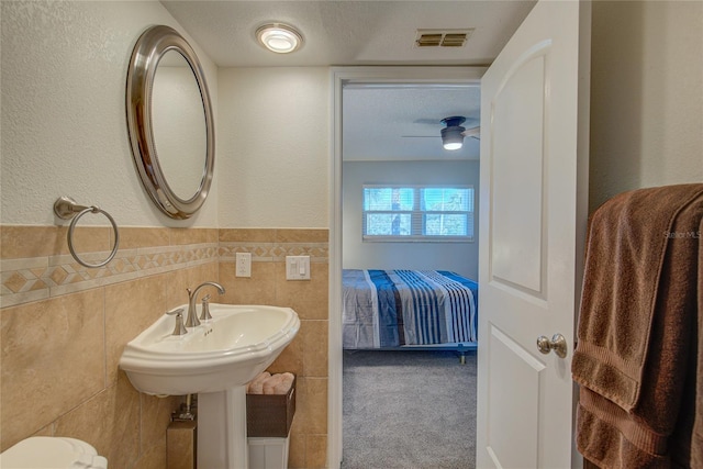 bathroom featuring sink, a textured ceiling, tile walls, and ceiling fan