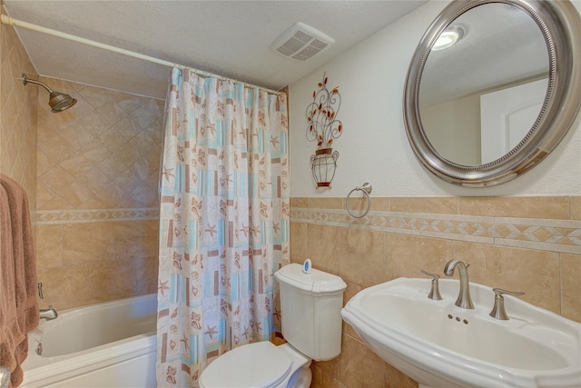 full bathroom featuring shower / tub combo, a textured ceiling, tile walls, and sink