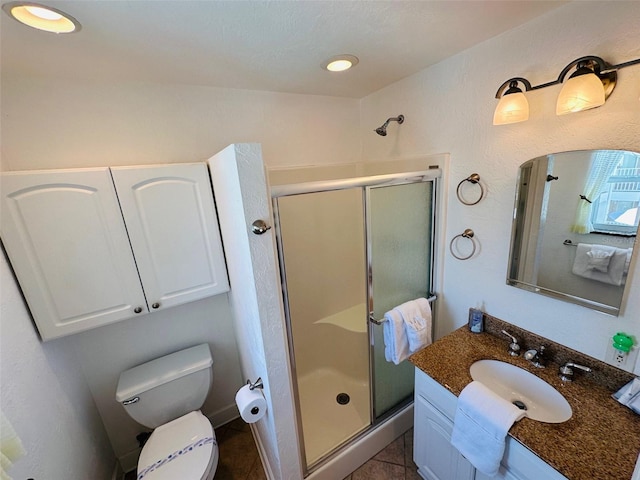 bathroom featuring tile floors, a shower with shower door, toilet, and vanity