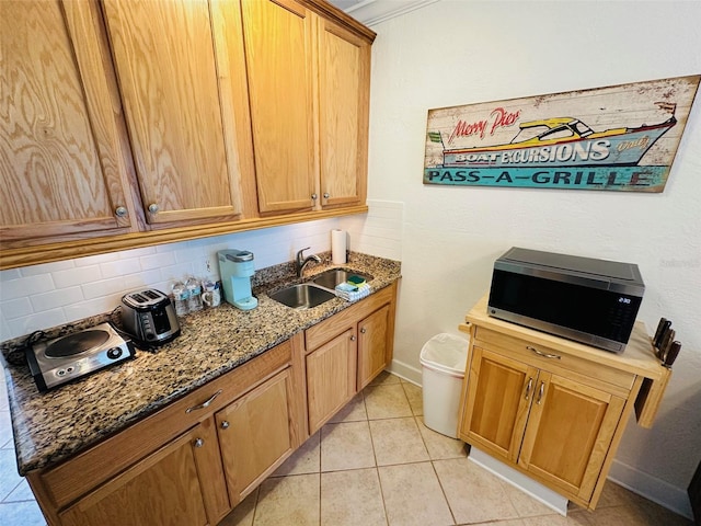 kitchen with sink, stone counters, tasteful backsplash, and light tile floors