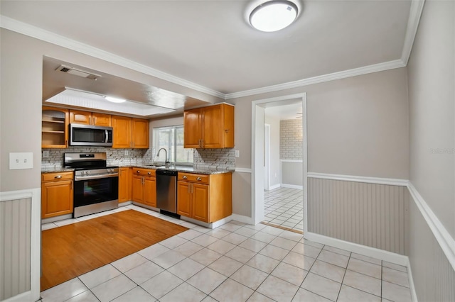 kitchen with sink, crown molding, decorative backsplash, light tile patterned flooring, and appliances with stainless steel finishes