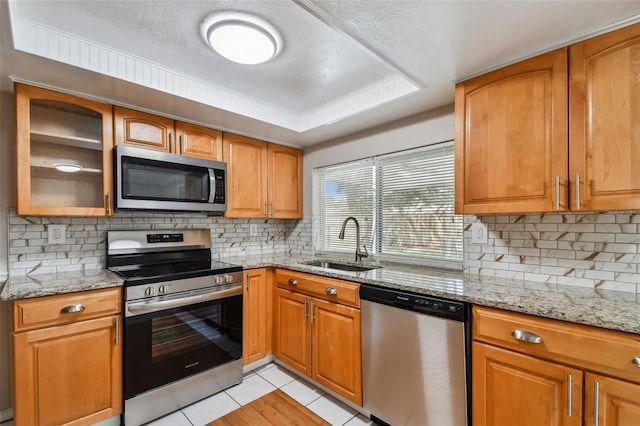 kitchen featuring light stone countertops, light tile patterned floors, stainless steel appliances, and sink