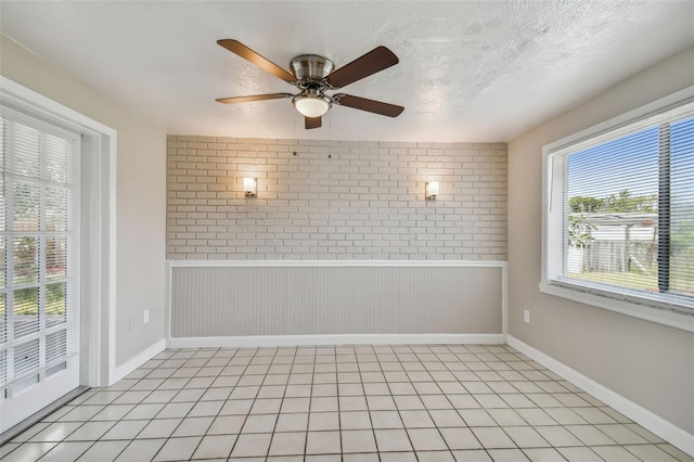 unfurnished room featuring ceiling fan, light tile patterned flooring, a textured ceiling, and wooden walls