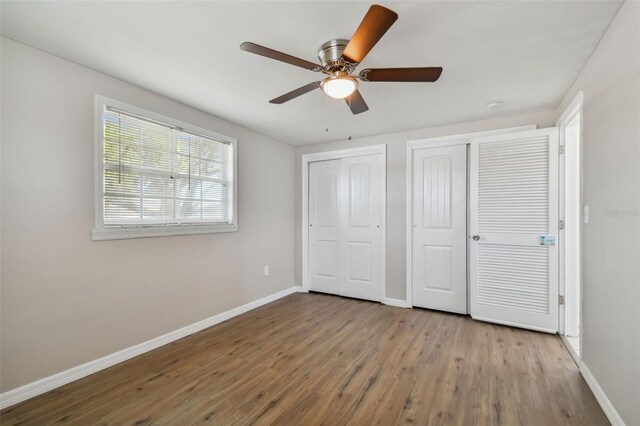 unfurnished bedroom featuring hardwood / wood-style flooring, ceiling fan, and two closets