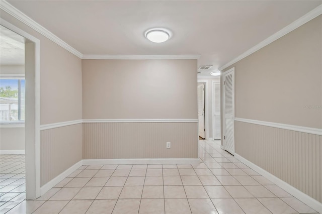 spare room featuring crown molding, wooden walls, and light tile patterned flooring