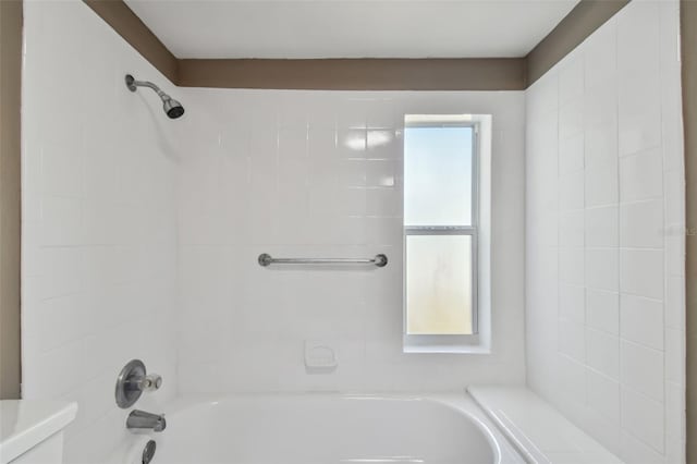 bathroom with toilet and tiled shower / bath