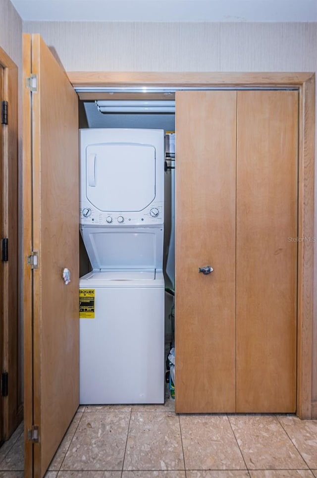 clothes washing area with stacked washing maching and dryer and light tile flooring