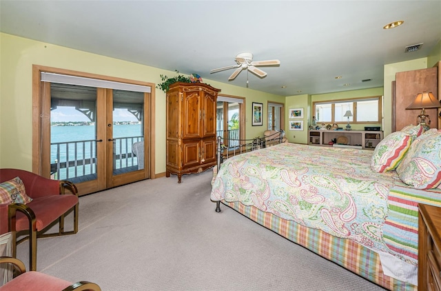 carpeted bedroom featuring access to outside, french doors, ceiling fan, and a water view