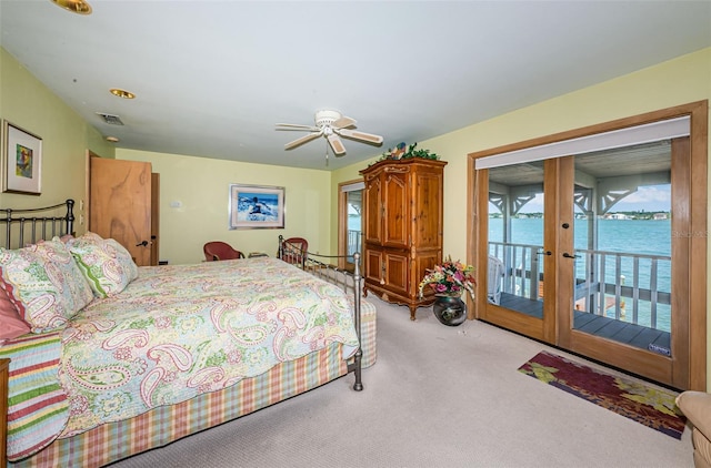 carpeted bedroom with access to outside, french doors, ceiling fan, and a water view