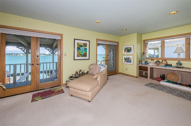 carpeted living room featuring a water view and french doors