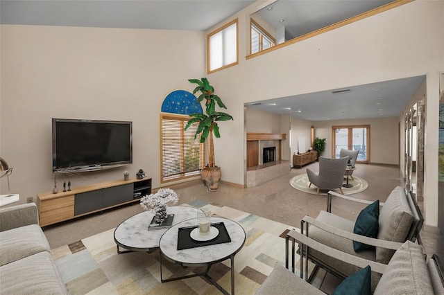 living area featuring visible vents, a towering ceiling, and a tiled fireplace